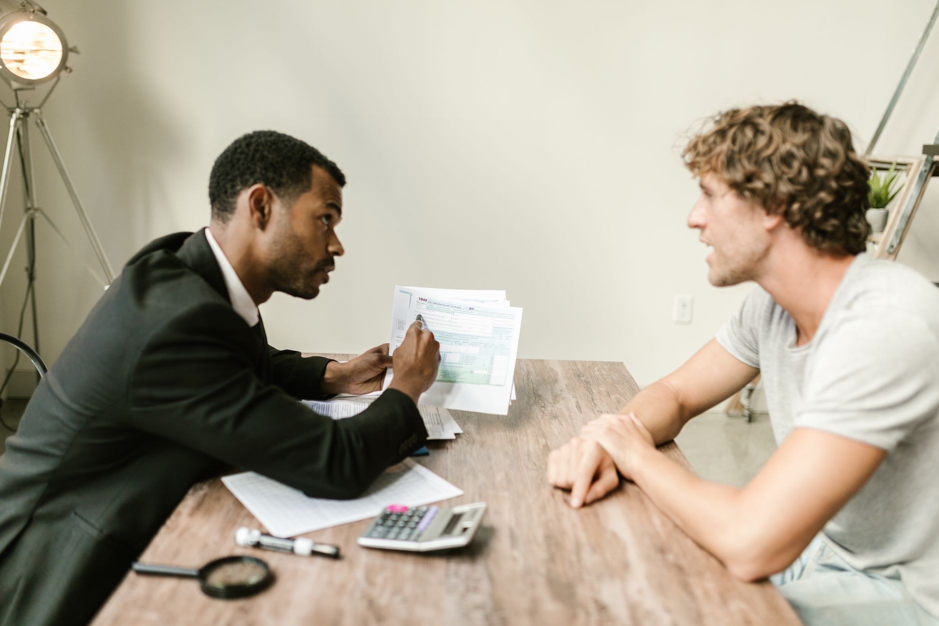 Two people across a table reviewing an application document, one examining it closely